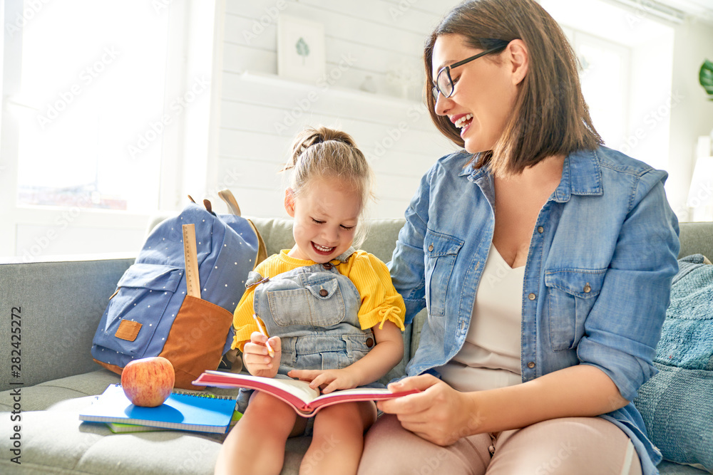 mother and her daughter are writing in notebook.