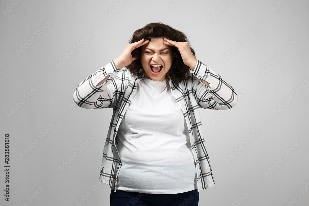 Stressed overweight woman on light background