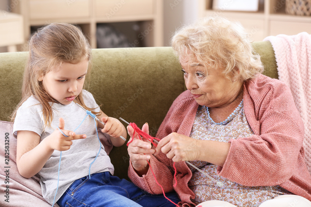 Cute little girl with grandmother knitting at home