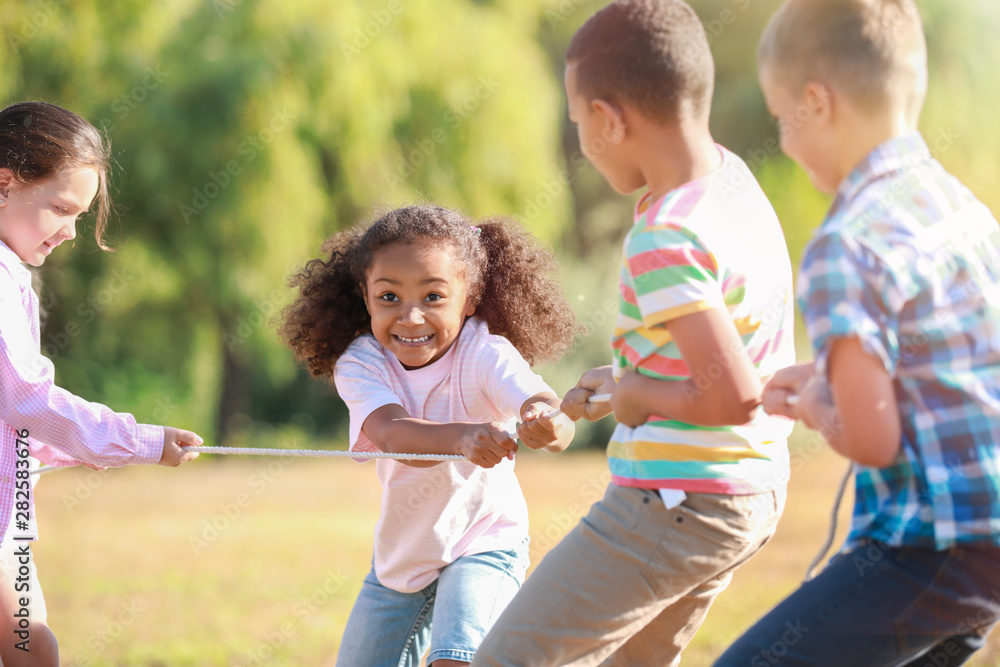 Group of little children pulling rope in park