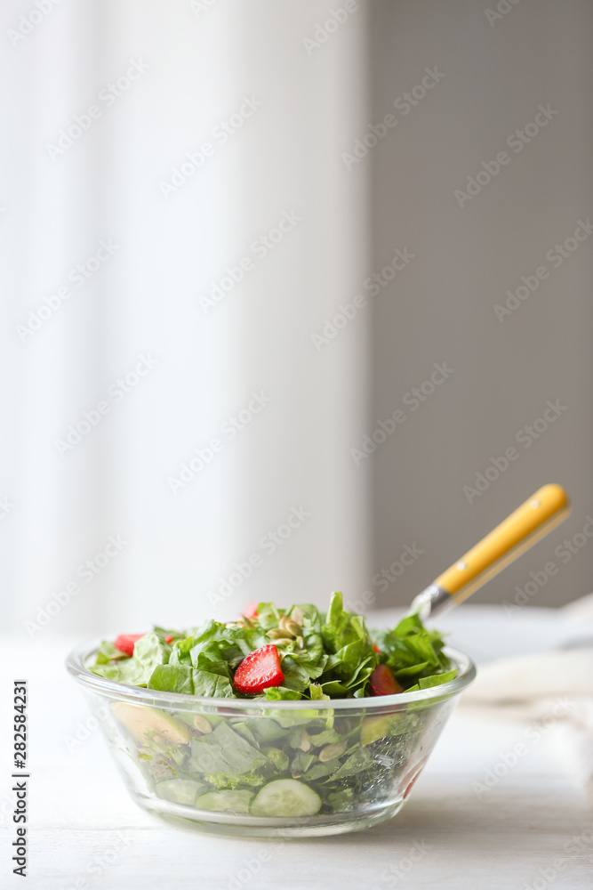 Bowl with fresh tasty salad on table