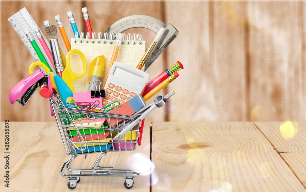 Stationery objects in mini supermarket cart on  background