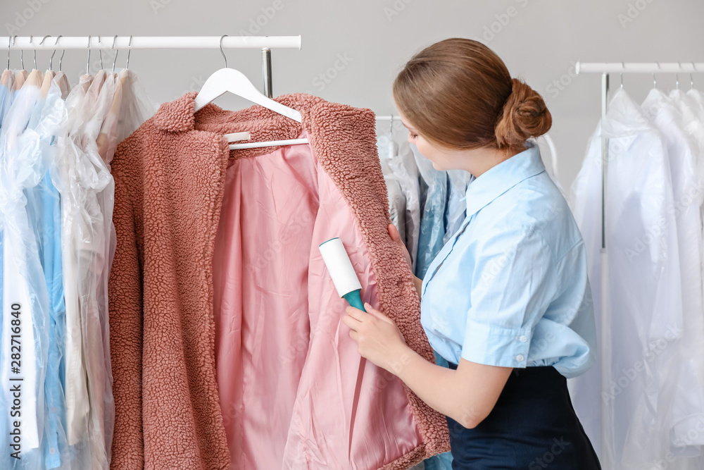 Woman removing dirt from clothes in modern dry-cleaners