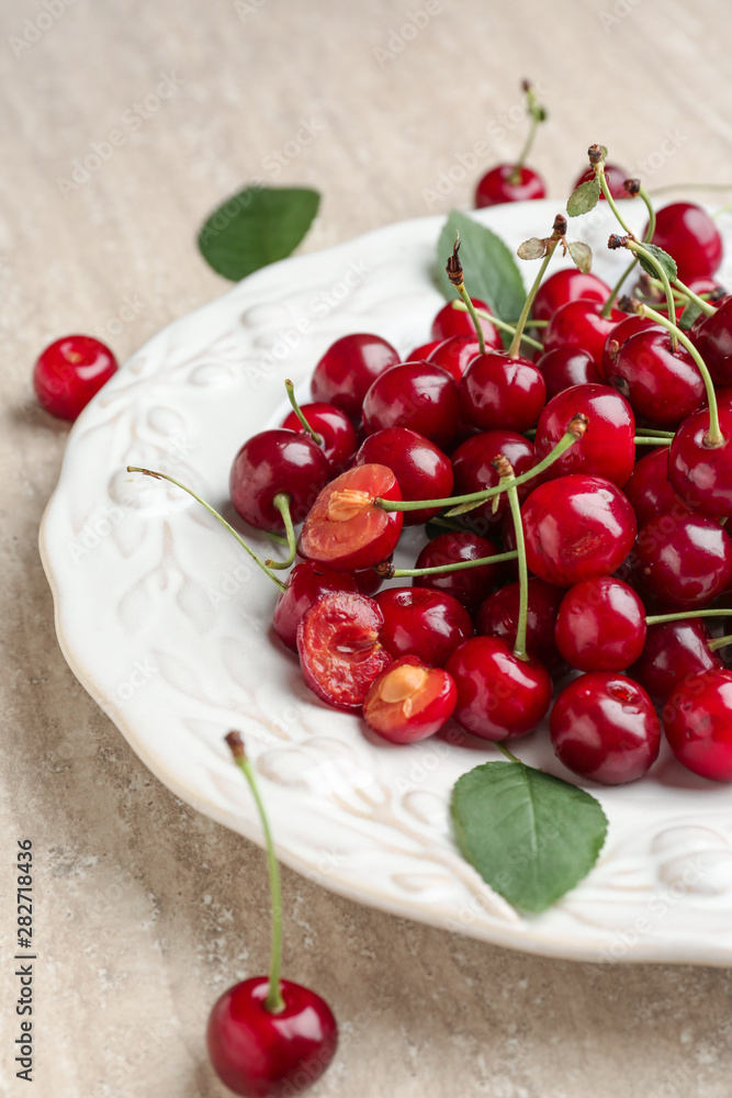 Plate with ripe cherry on table