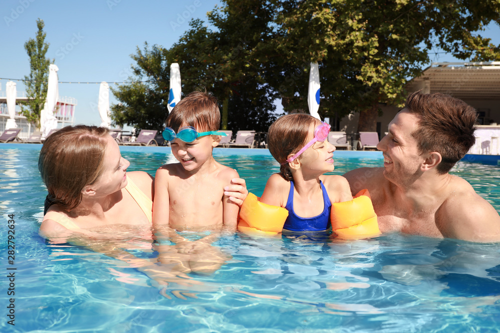 Happy family in swimming pool on summer day