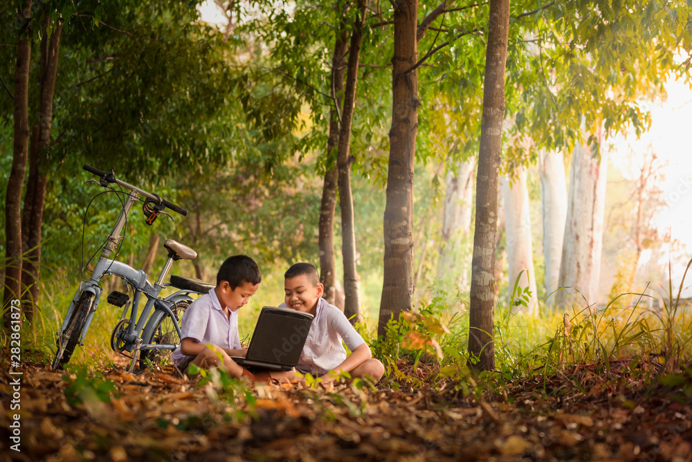 Smiling Asian boys using a laptop for education Choose focus on the eyes with a blurred background.