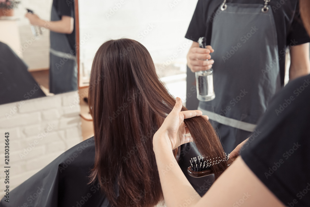 Female hairdresser working with client in salon, closeup