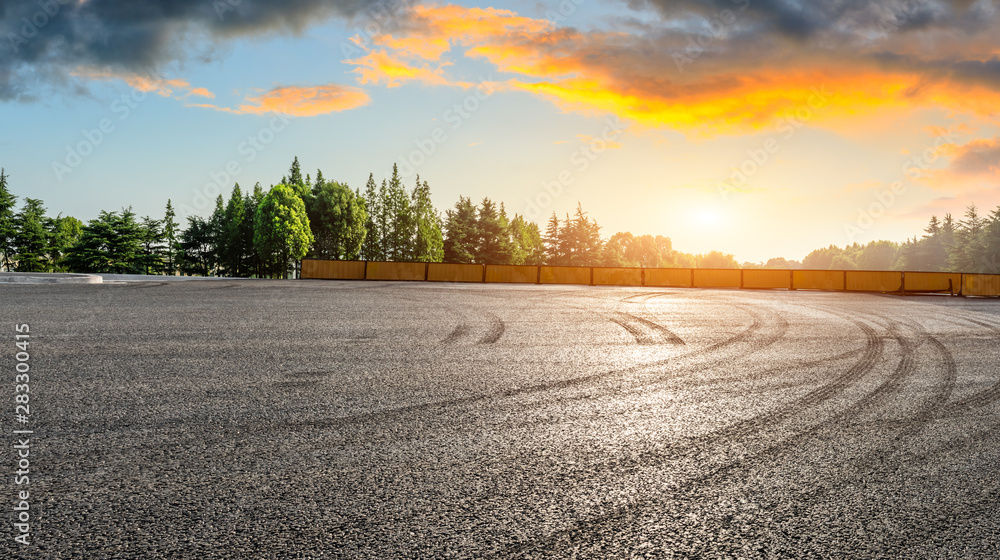 Asphalt race track and green woods nature landscape at sunset