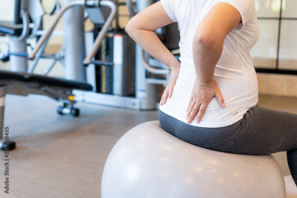 Active pregnant woman exercise in fitness center at yoga room. The young expecting mother holding ba