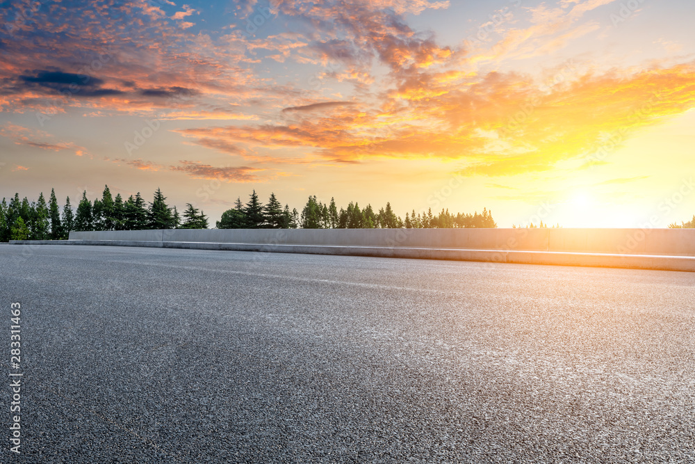 Country asphalt road and green woods nature landscape at sunset