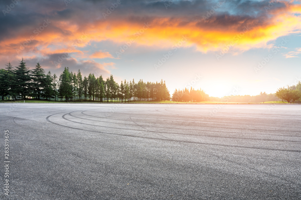 Asphalt race track and green woods nature landscape at sunset