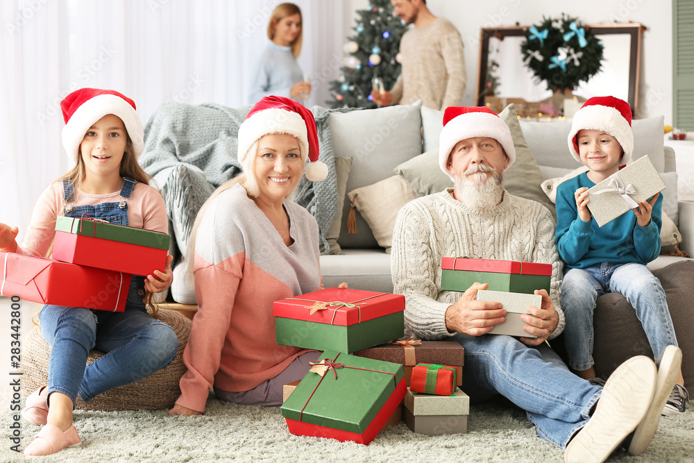 Happy grandparents and little children with Christmas gifts at home