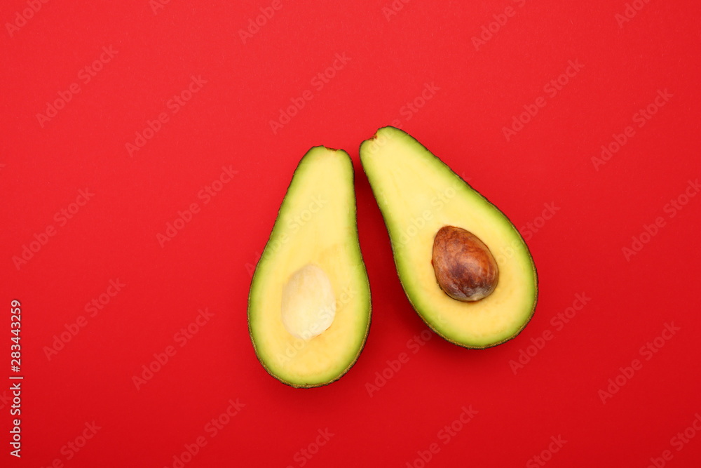 Halves of ripe avocado on color background