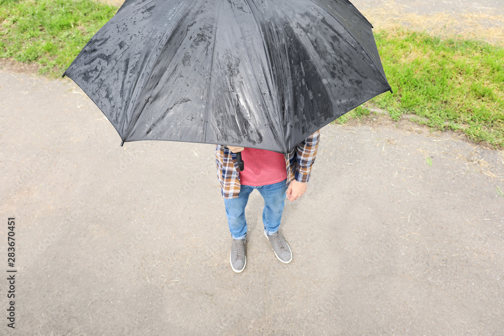 Handsome man with umbrella outdoors