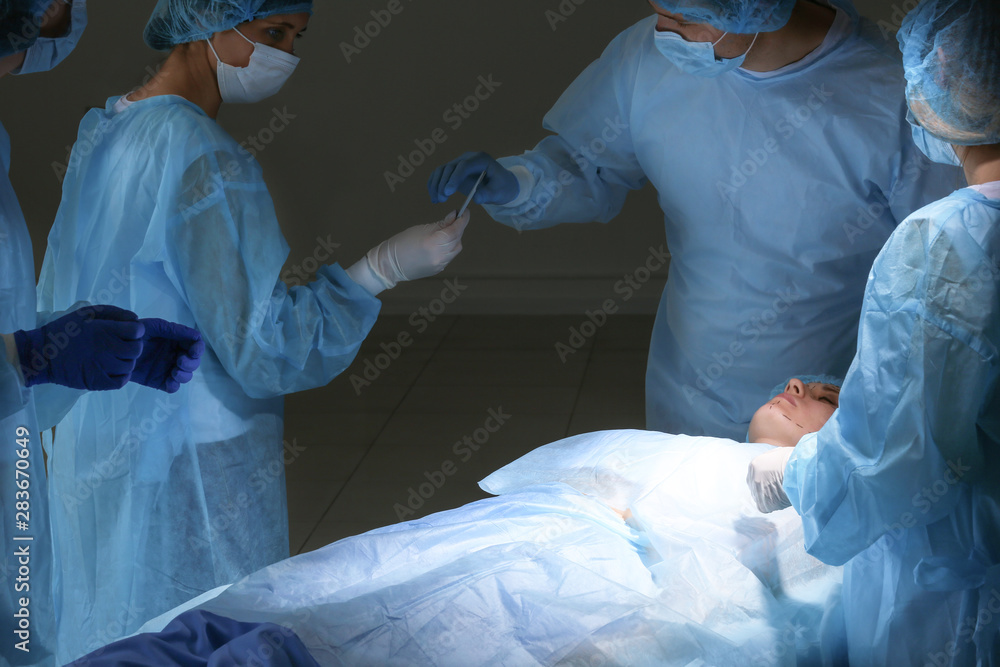 Plastic surgeons operating patient in clinic