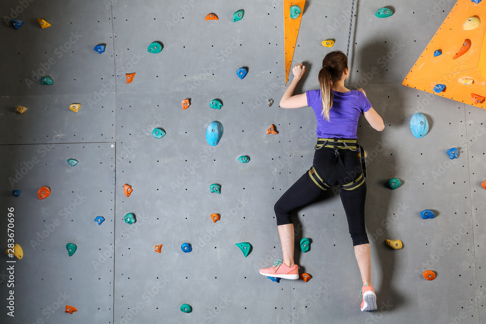 Young woman climbing wall in gym