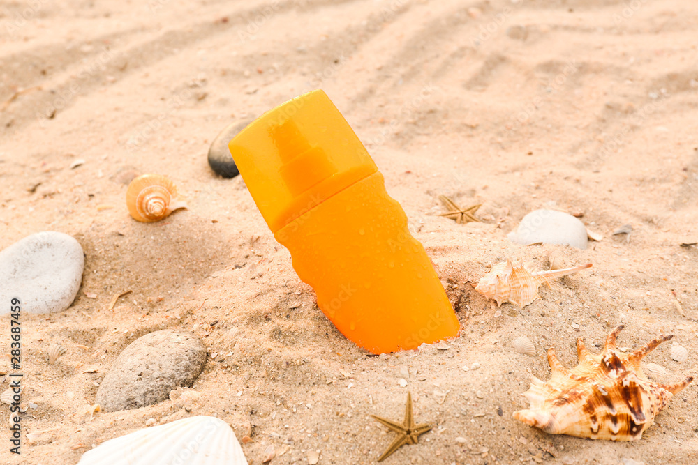 Bottle of sunscreen cream on sand beach