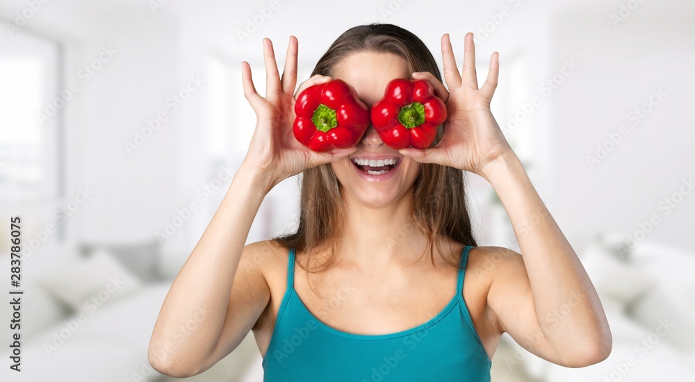 Beautiful laughing woman holding two ripe tomatoes before her eyes.