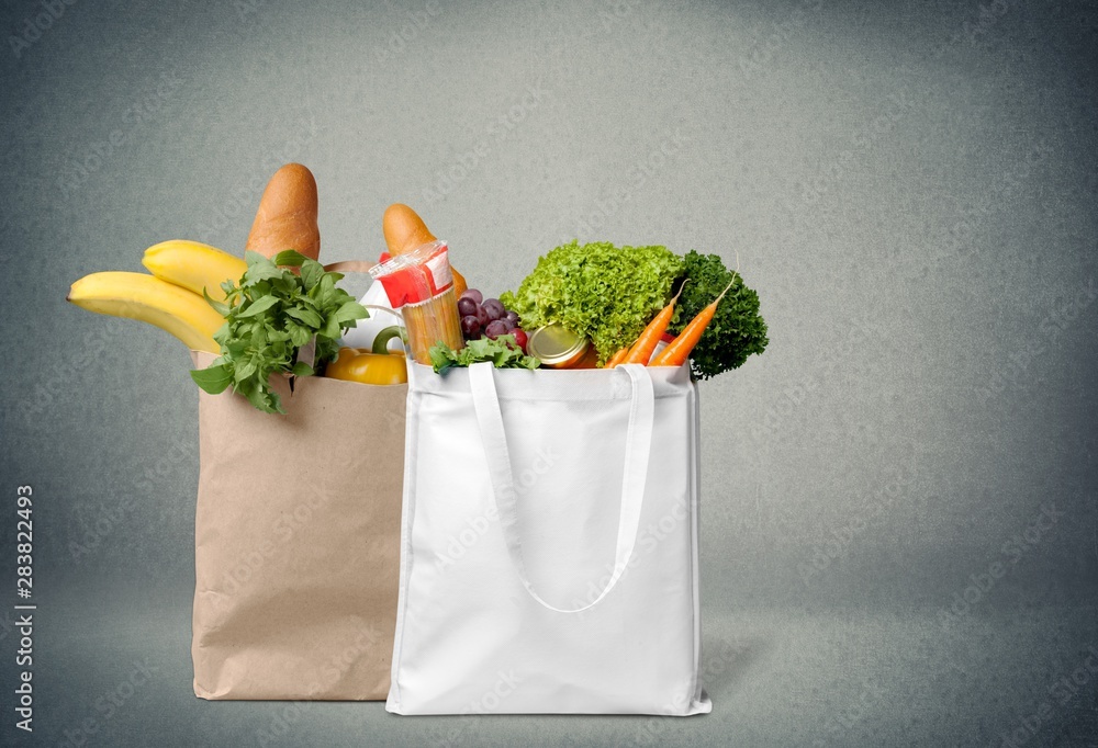 Shopping bags with groceries on stone background