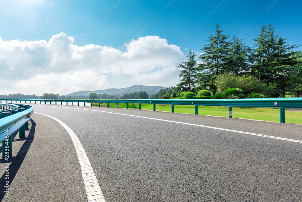 Country asphalt road and green woods with mountain nature landscape in summer