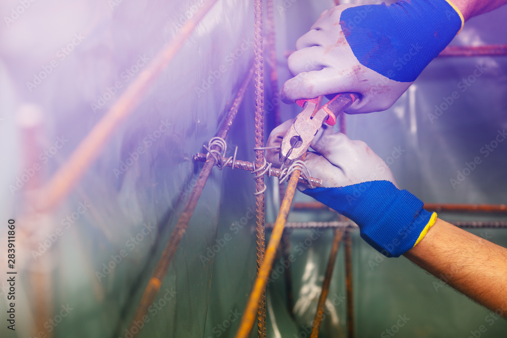 Closeup of man hands knit metal rods for basement