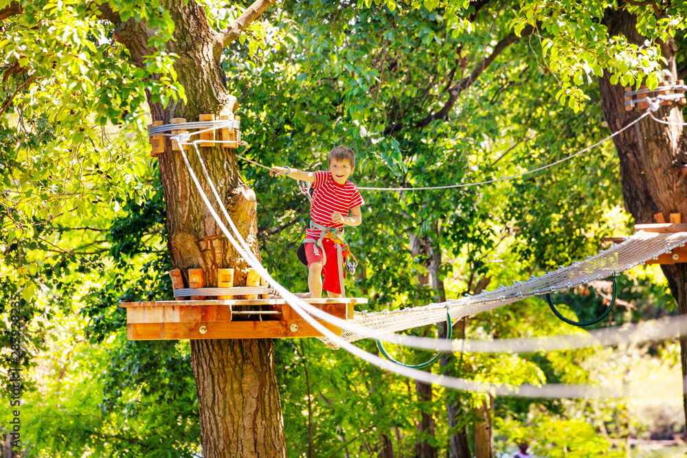 Boy passes line and suspended bridge at rope park