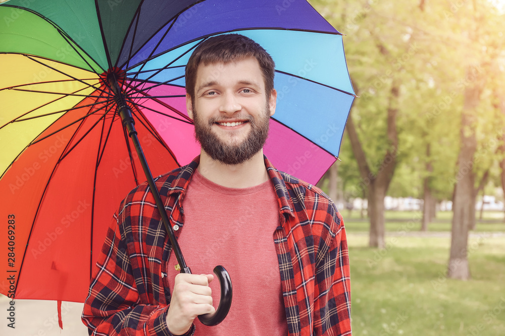 Handsome man with colorful umbrella outdoors