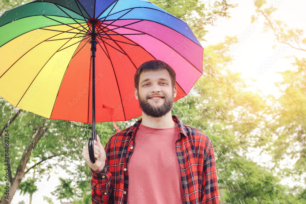 户外带着五颜六色雨伞的英俊男子