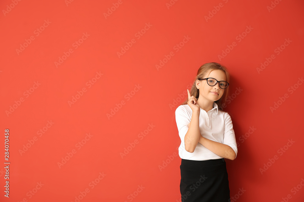 Little schoolgirl with raised index finger on color background