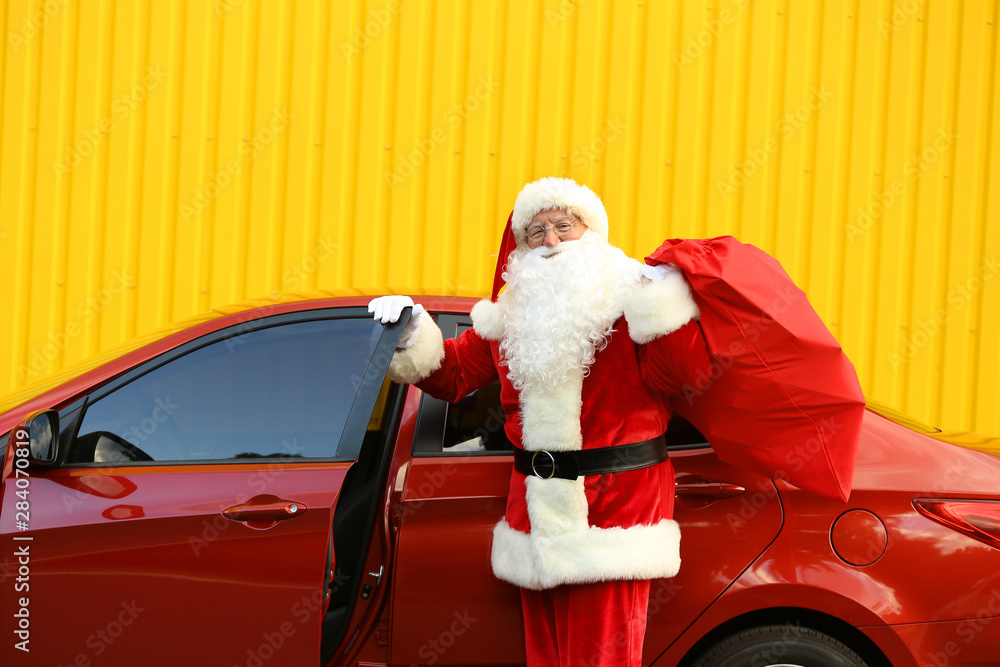 Santa Claus with gifts in bag near car outdoors