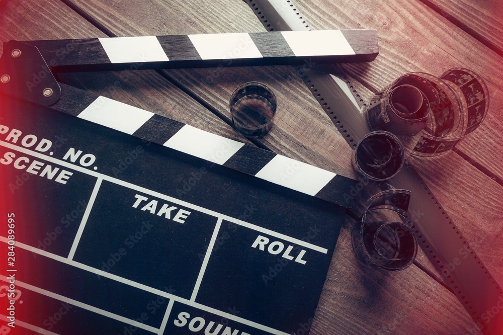 Movie clapper board and film tapes on wooden background