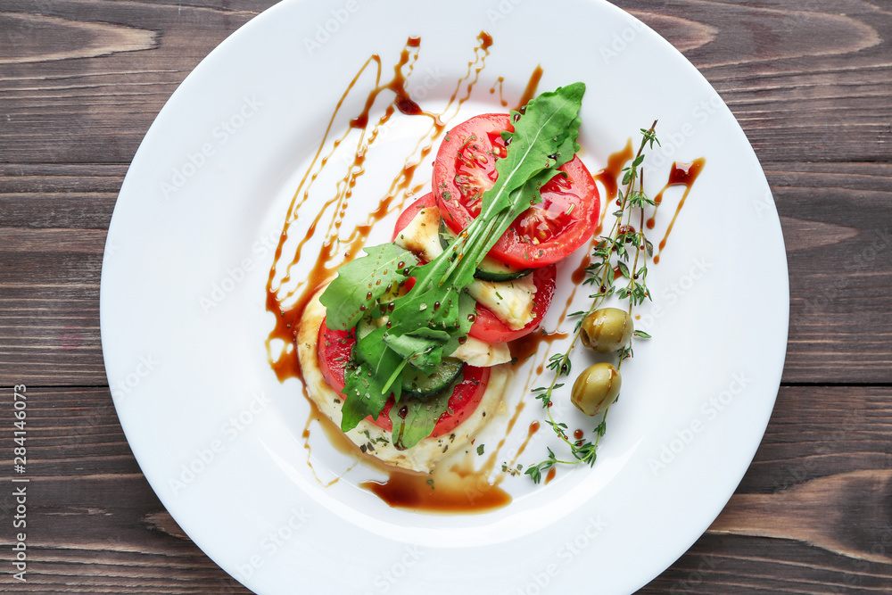 Plate with tasty salad on wooden background