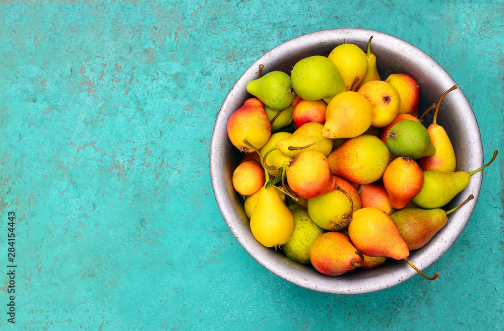 Fresh ripe organic pears in vintage metallic bowl on rustic blue green background.Autumn harvest,fru