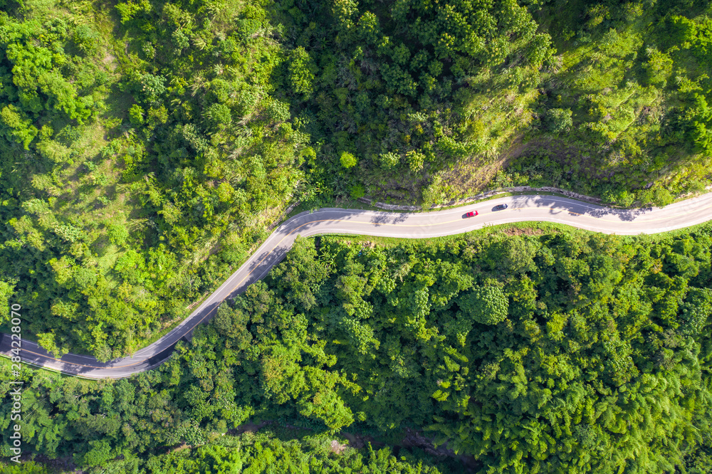 Aerial view of countryside road passing through the tropical rainforest and mountain in SouthEast As