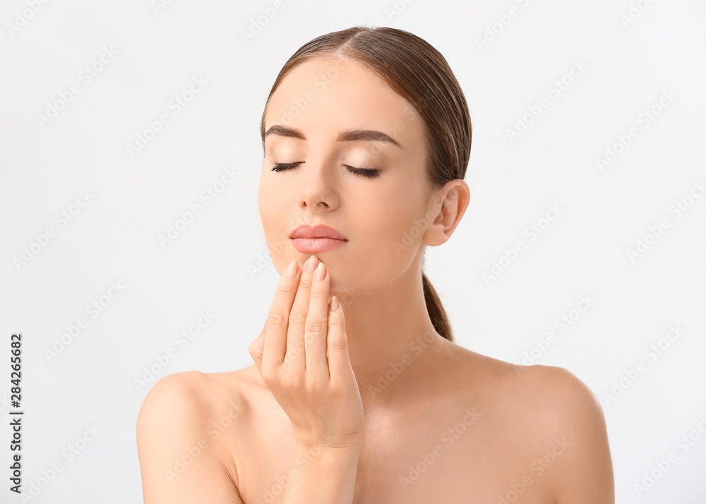 Beautiful woman massaging her face against white background