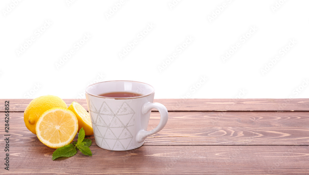 Cup of tasty tea with mint and lemon on wooden table against white background