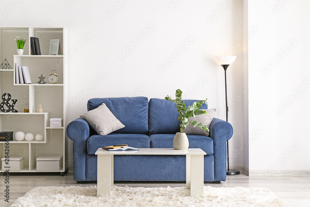 Stylish interior of room with sofa and eucalyptus branches in vase on table