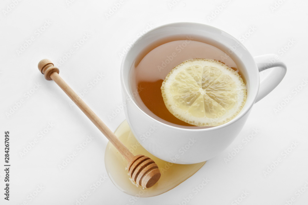 Cup of tasty tea with honey and lemon on white background