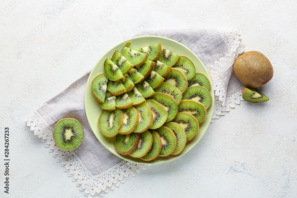 Plate with tasty ripe kiwi on white background