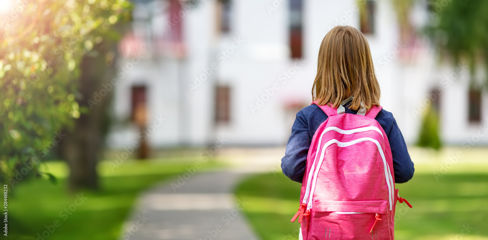 学校大楼前背着帆布背包的女孩