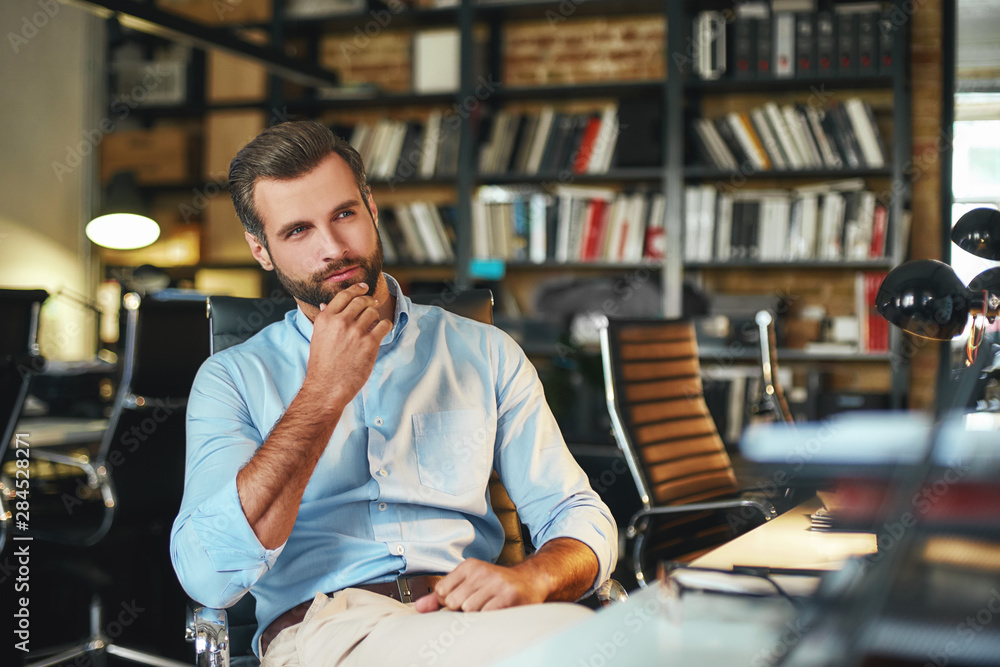 New ideas. Young bearded businessman in formal wear touching his chin and thinking about something w