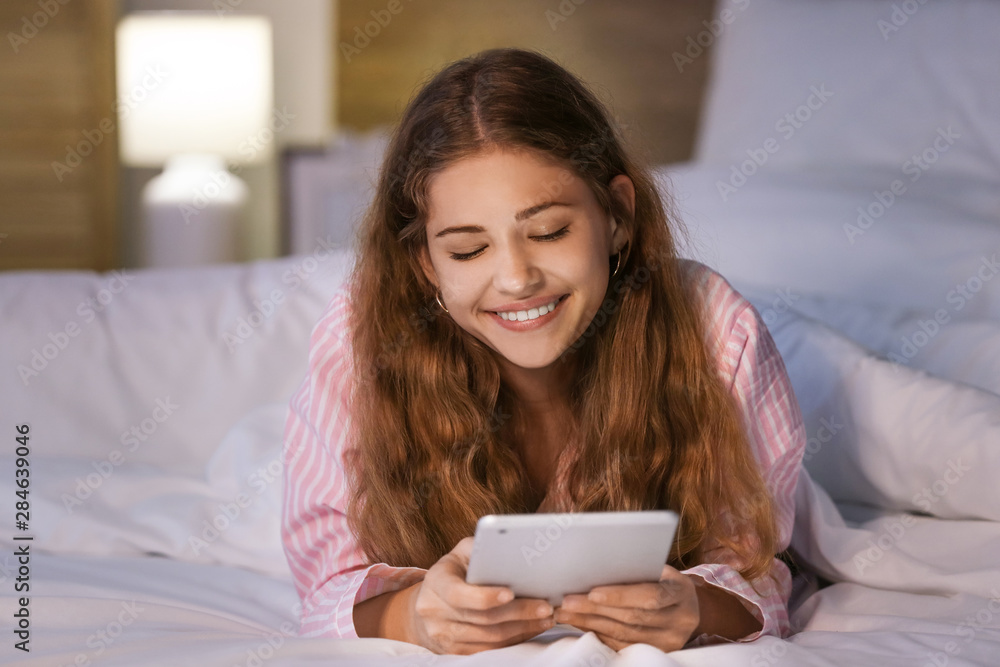 Teenage girl with tablet computer in bed at night