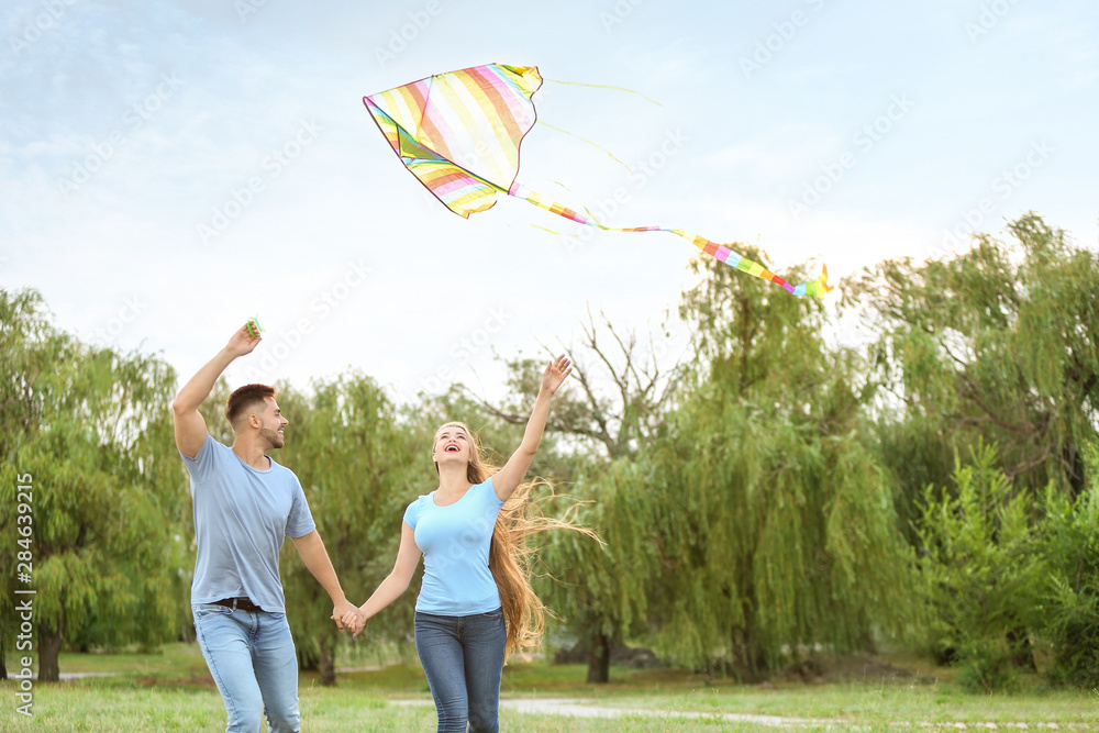 Happy young couple flying kite outdoors