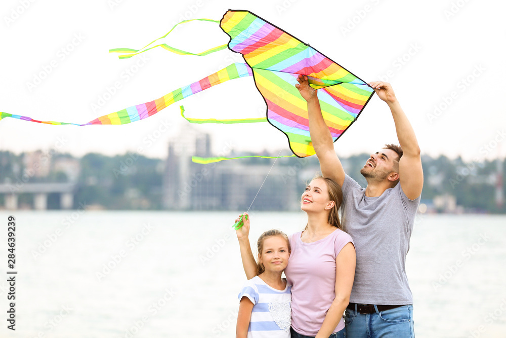 Happy family flying kite near river