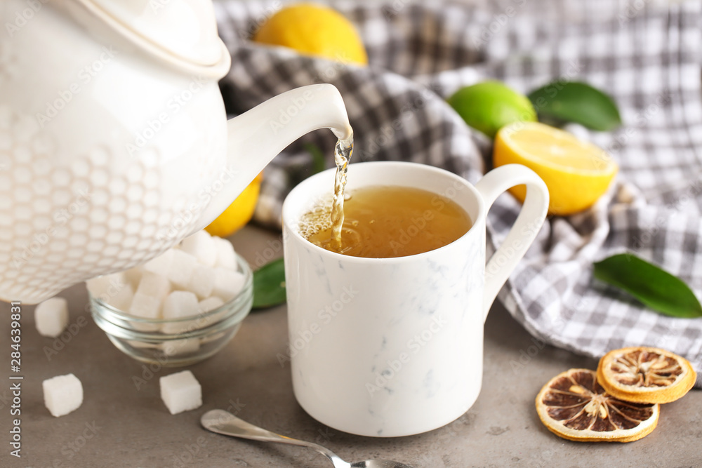 Pouring of hot tea in cup on table