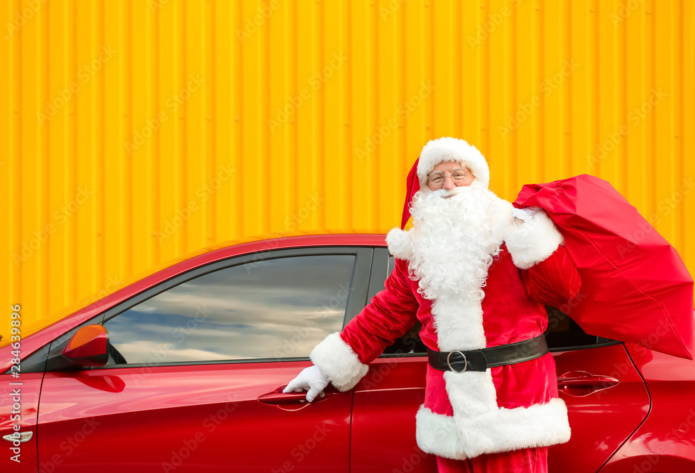 Santa Claus with gifts in bag near car outdoors