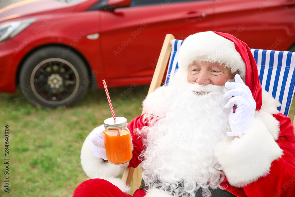 Cool Santa Claus with cocktail talking by mobile phone outdoors