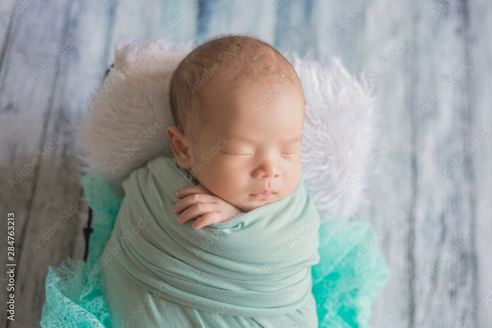 Adorable newborn baby sleeping in cozy room. Cute happy infant baby portrait with sleepy face in bed