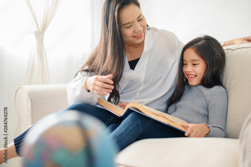 mother and child daughter doing homework  and reading at home