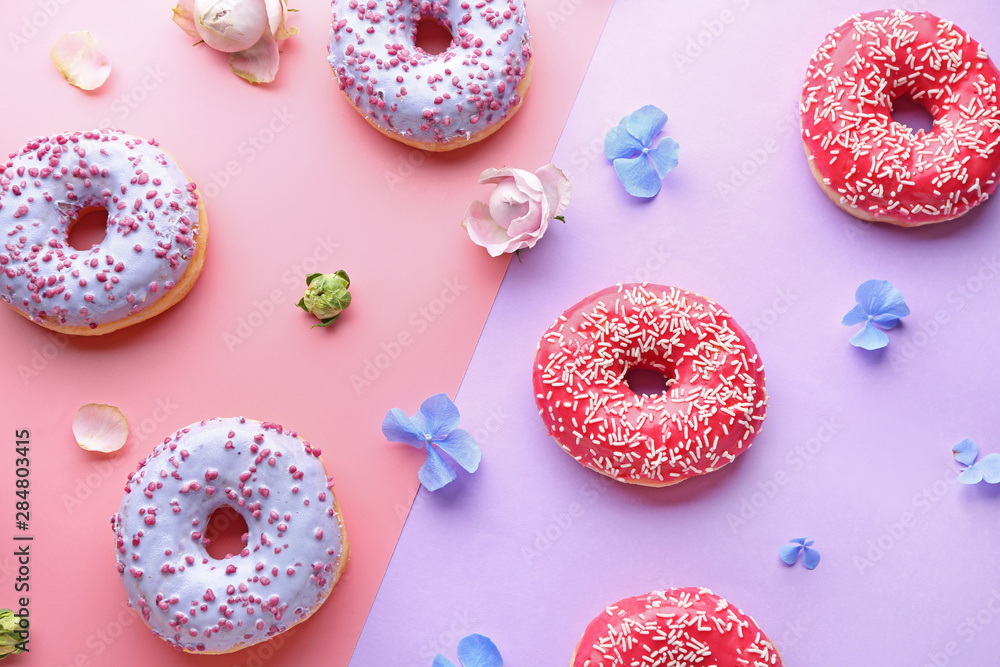 Sweet tasty donuts and flowers on color background